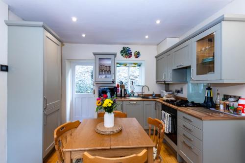 a kitchen with a wooden table with flowers on it at The Snug - A Quaint Mews Cottage City Centre in Wells