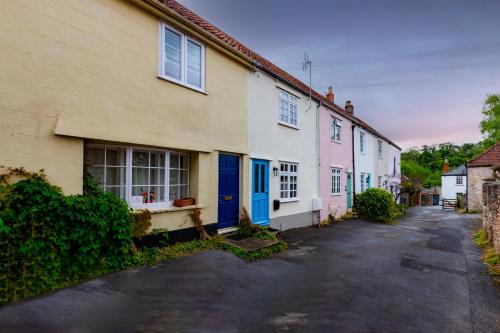 a row of houses with blue doors on a street at The Snug - A Quaint Mews Cottage City Centre in Wells