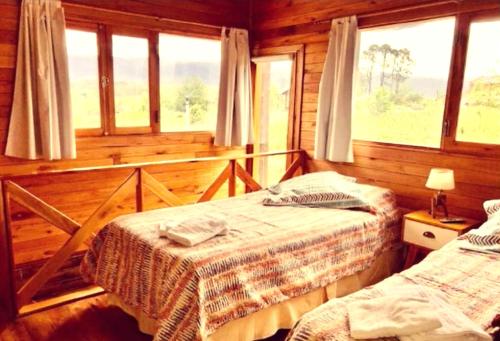 a bedroom with two beds in a log cabin at Cabaña Snowflakes in Villa Yacanto
