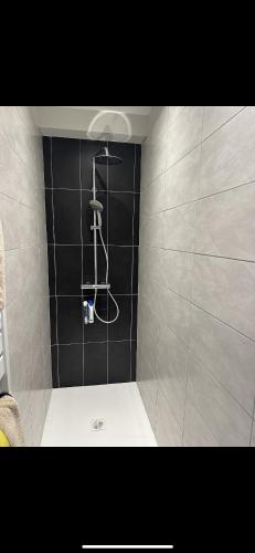 La salle de bains est pourvue d'une douche et d'un mur en carrelage noir. dans l'établissement Appartement avec un agréable point de vue et quartier calme, à Brive-la-Gaillarde