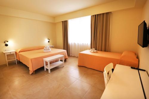 a hotel room with two beds and a television at Verdello Home Savoca in Savoca 