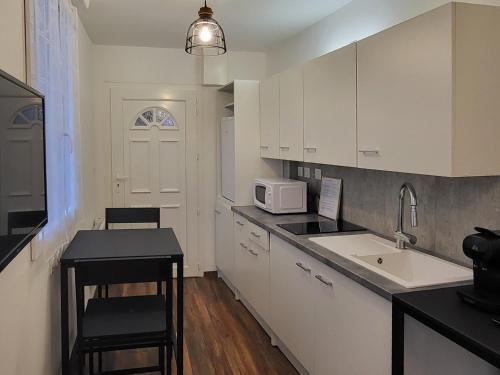 サン・クロードにあるAppartement 2 Coin cuisine, coin chambre, salle de bainの白いキャビネットとシンクと電子レンジを備えたキッチン