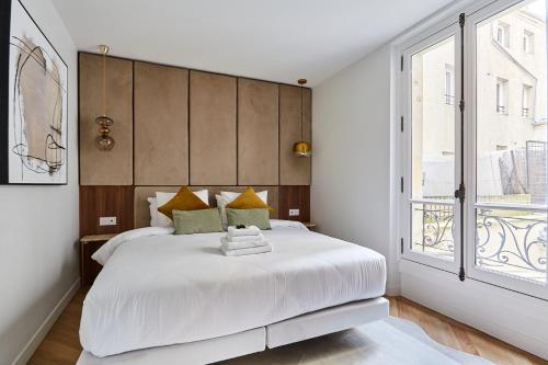 une chambre avec un grand lit blanc et une fenêtre dans l'établissement Residence 2 Apartments Center of Paris by Studio Prestige, à Paris