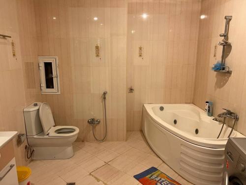 a bathroom with a tub and a toilet and a sink at Sea view couple apartmant at boulvard,near nizami street in Baku