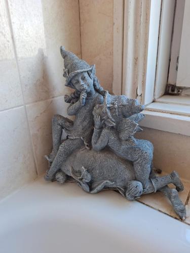 a statue of two elves sitting on a rock next to a window at 'Aandal House' Bournemouth' in Parkstone