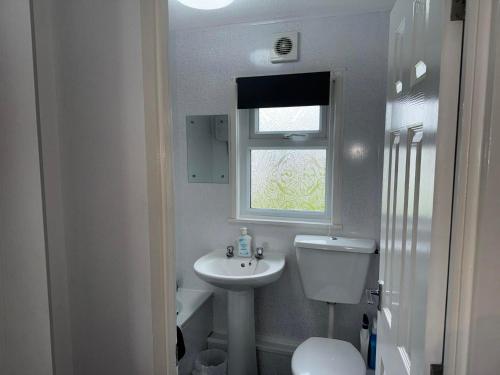 a bathroom with a sink and a toilet and a window at 103 Sunbeach South facing 2 bed chalet M and T chalets in Great Yarmouth