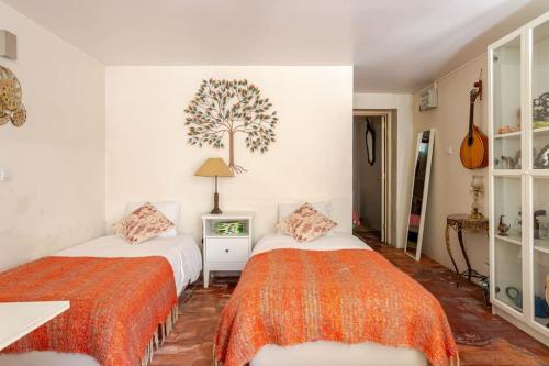 een slaapkamer met 2 bedden en een boom aan de muur bij Studio & Garden in Lissabon