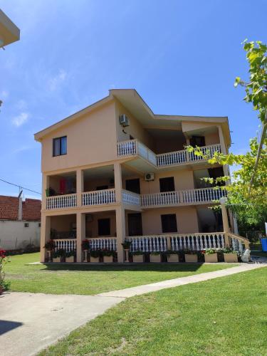 a large yellow building with a porch and balcony at Apartments Marniku in Ulcinj