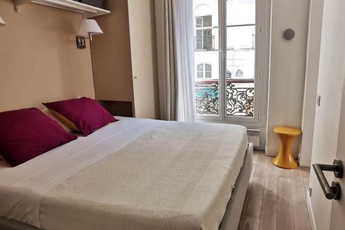 une chambre avec un grand lit blanc et une fenêtre dans l'établissement Appartement Place des Vosges, 1 chambres 4 P, à Paris
