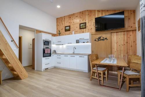 a kitchen with white cabinets and a wooden wall at Villa Garden in Bešeňová
