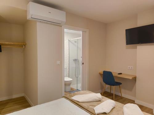 a bedroom with a bed and a desk and a bathroom at Villa Galicia (Padrón) in Padrón