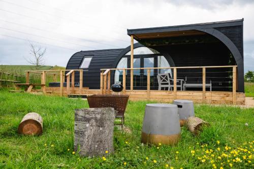 a black and wooden house in a field with grass at Kite Lodge in Little Bytham