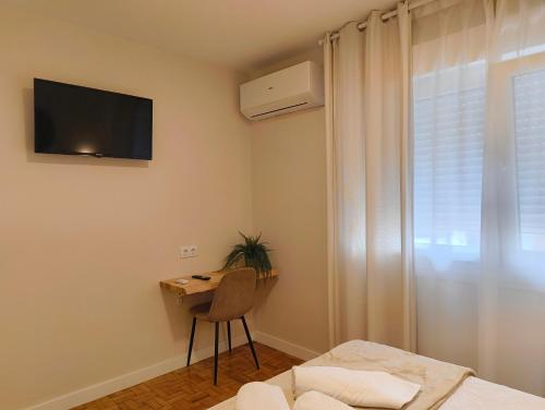 a bedroom with a bed and a desk and a television at Villa Galicia (Padrón) in Padrón