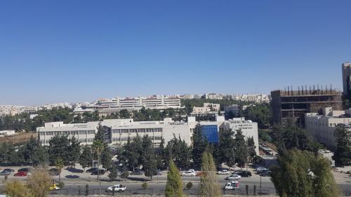 a large white building with a parking lot at Al Khaleej Hotel Apartments in Amman