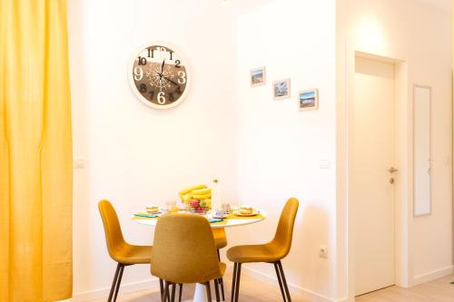 a dining room table with chairs and a clock on the wall at Lussin in Mali Lošinj