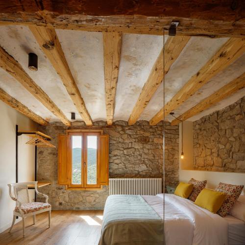a bedroom with a bed and a stone wall at Masia la Oliva in Coll de Nargó