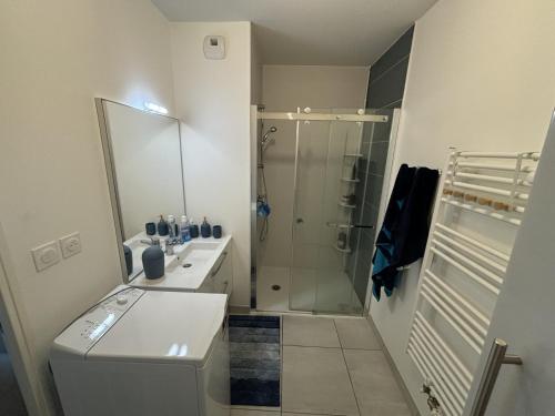 Un baño blanco con ducha y lavabo. en Appartement Biscarrosse, en Biscarrosse
