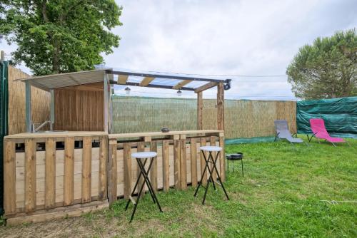 une cour avec une clôture en bois et une pergola dans l'établissement Tipi Expérience L'échappée Belle, à Saint-Maudez