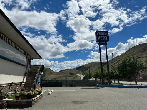 a sign in a parking lot next to a motel at Riverside Motel Cache Creek in Cache Creek