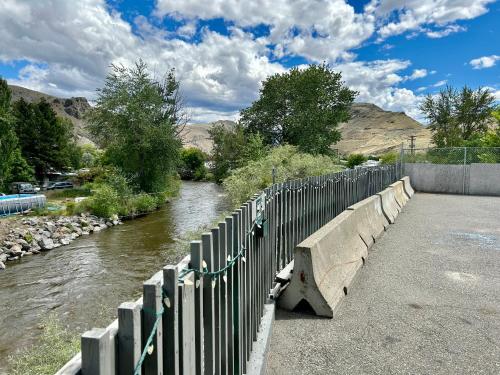 a bridge with a fence next to a river at Riverside Motel Cache Creek in Cache Creek
