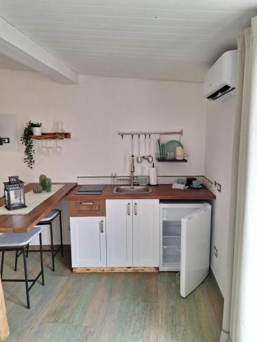 a kitchen with white cabinets and a sink and a table at Casa vacanze green house in Terrasini