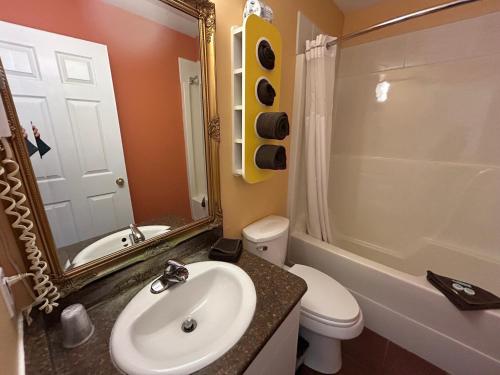 a bathroom with a sink and a toilet and a mirror at Riverside Motel Cache Creek in Cache Creek