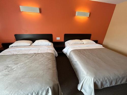 two beds in a room with orange walls at Riverside Motel Cache Creek in Cache Creek