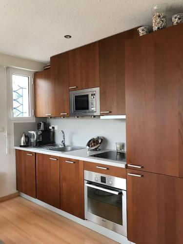 une cuisine avec des armoires en bois et des appareils en acier inoxydable dans l'établissement Appartement T2 Les papillons, à Arcachon