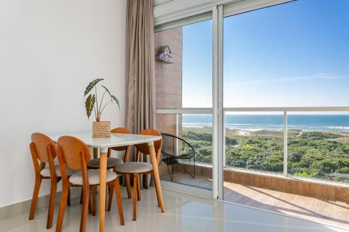 uma sala de jantar com mesa e cadeiras e uma grande janela em Apartamento Vista Mar no Novo Campeche em Florianópolis