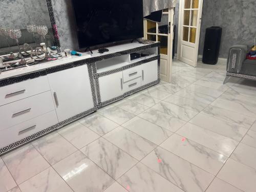 een witte marmeren vloer in een kamer met een tv bij La maison in Monsols