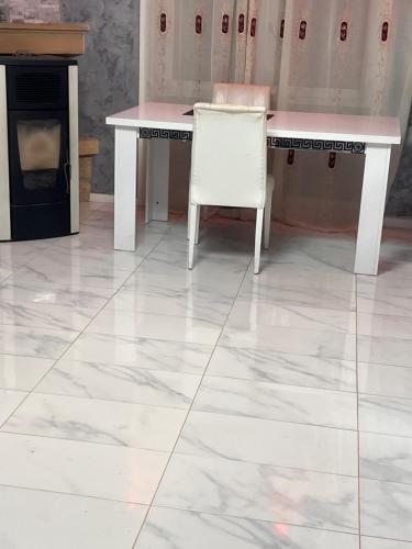 een witte tafel en een witte stoel op een tegelvloer bij La maison in Monsols