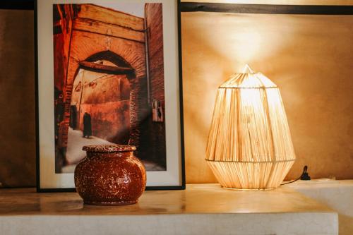 a lamp and a vase on a table next to a painting at Hotel & Spa La Ferme El Dar in Marrakech