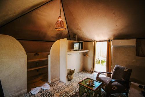 a room with a refrigerator and a chair and a table at Hotel & Spa La Ferme El Dar in Marrakech