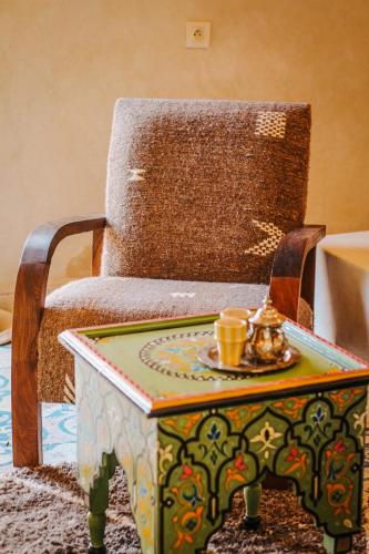 a table with a chair and a tableasteryasteryasteryasteryasteryasteryasteryastery at Hotel & Spa La Ferme El Dar in Marrakech