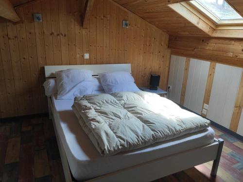 a white bed in a room with a wooden ceiling at Petit gite paisible en bord de lac in Saint-Gérons