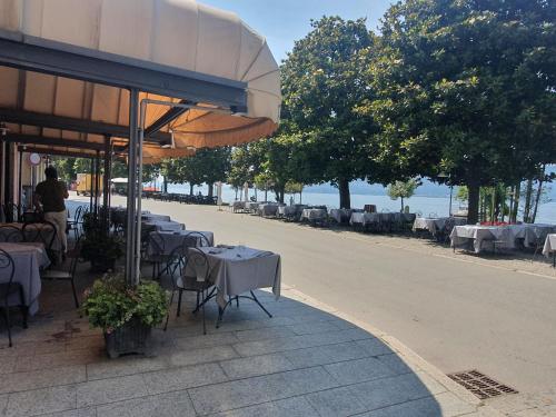 a row of tables and chairs with umbrellas on a street at Appartamenti vicino al lago con bikeparking in Verbania