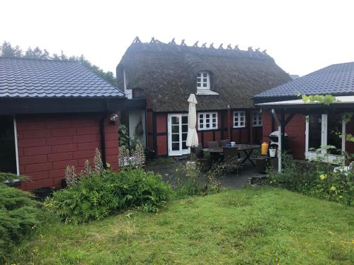 a small red house with a table in the yard at Hyggeligt gammelt hus i Ry in Ry