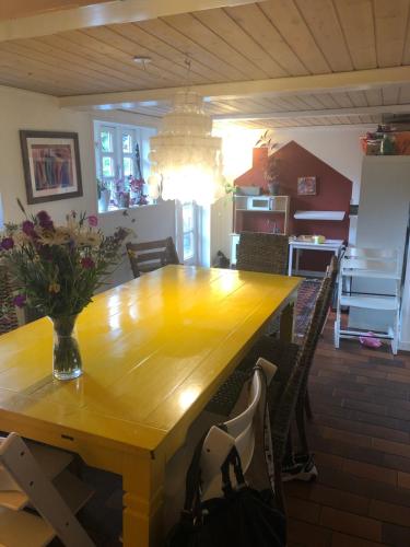 a dining room table with a vase of flowers on it at Hyggeligt gammelt hus i Ry in Ry