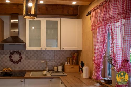 een keuken met witte kasten en een rood geblokt gordijn bij Carski raj in Bribir