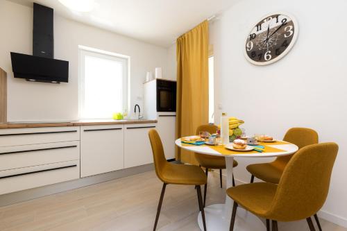 a kitchen with a table and chairs and a clock on the wall at Lussin in Mali Lošinj