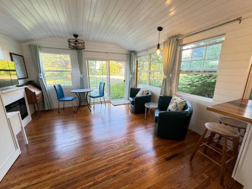 a living room with wooden floors and chairs and a table at Acadia Seaside Bungalow in Tremont