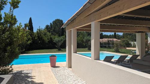 un patio avec des chaises et une piscine dans l'établissement Gîte climatisé avec piscine et pétanque aux portes d'Aix en Provence, à Éguilles