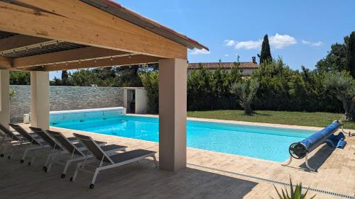 une piscine avec des chaises et un gazebo dans l'établissement Gîte climatisé avec piscine et pétanque aux portes d'Aix en Provence, à Éguilles