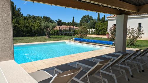 une piscine dans une cour avec des chaises autour dans l'établissement Gîte climatisé avec piscine et pétanque aux portes d'Aix en Provence, à Éguilles