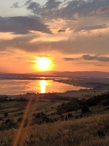 a sunset over a body of water with the sun setting at Panoramic House in Coronini