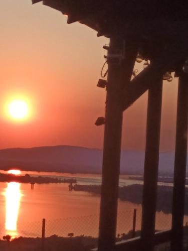 a sunset over the beach with a fence at Panoramic House in Coronini