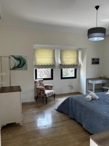 a bedroom with a bed and a chair and windows at Villa Mulberry - Kyrenia North Cyprus in Lapithos