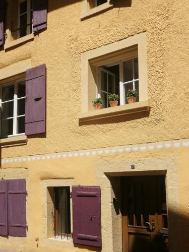 two windows with purple shutters and potted plants on them at La Bergerie in La Neuveville