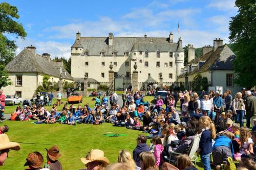 a crowd of people sitting on the grass in front of a castle at Glede Knowe Guest House in Innerleithen