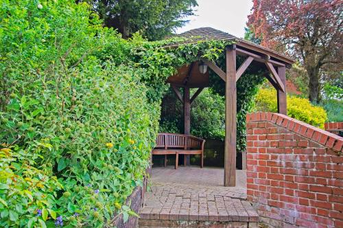 a bench sitting under a gazebo in a garden at Waveney House Hotel in Beccles